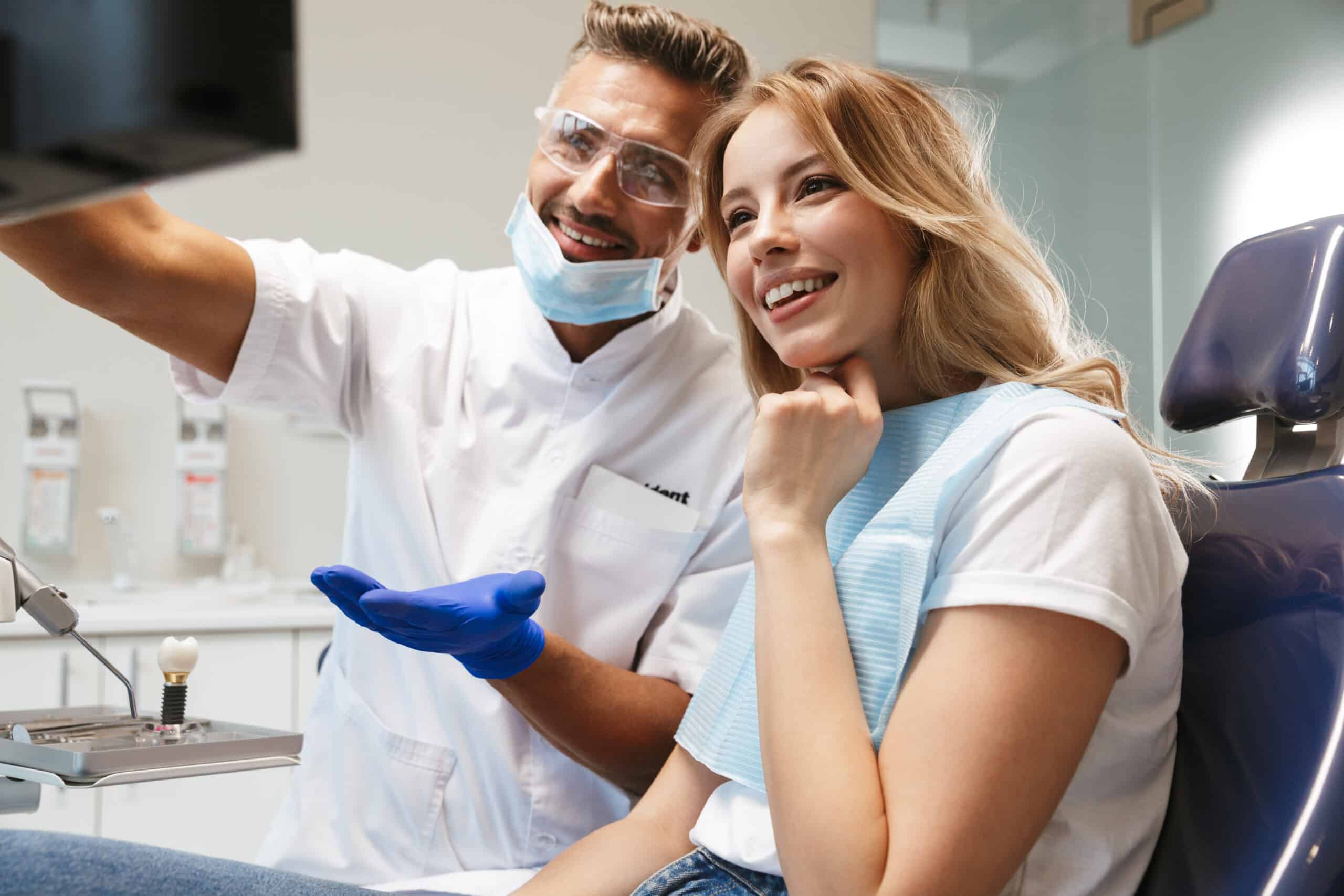 Happy young woman sitting in medical dentist center looking at x ray scan.